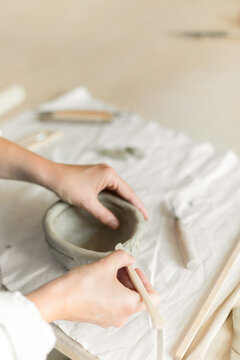 Woman potter meticulously shaping clay in a studio setting