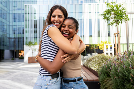 Diverse friends hugging laughing together in urban park