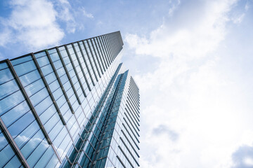 Fototapeta premium Low angle view of a striking glass skyscraper rising toward a dramatic blue sky in Brussels with generous copy space, showcasing contemporary corporate architecture and urban innovation