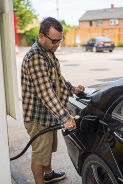 Corby, Northamptonshire, UK - August 2, 2026: Man driver refueling black car at gas station