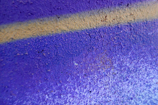 Urban graffiti wall with purple spray paint texture with one yellow line