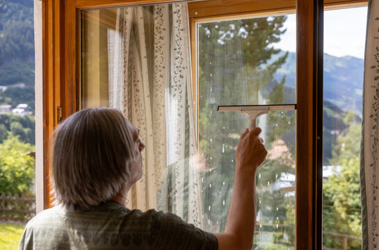 Mature man clean apartment window with squeegee