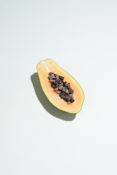 Papaya half with seeds on white background and shadow