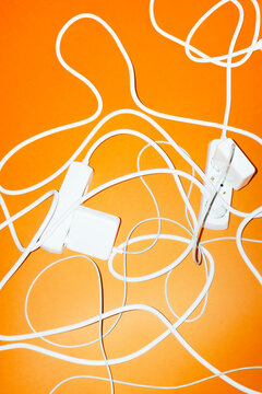 Tangled white extension cord and power adapter on orange