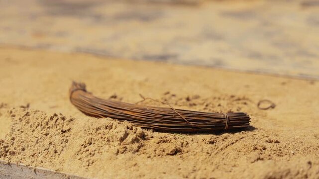 Close up of a bundle of old, rusted steel wire resting on yellow sand at a construction site, with soft focus on the background showing the texture and industrial environment