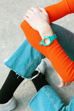 Top view of turquoise watch with orange sleeve and denim