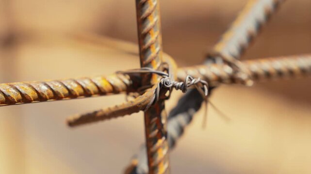 Close up detail of a rusty steel rebar framework at a construction site, showing the reinforcing iron bars tied together with wire for building a solid concrete foundation
