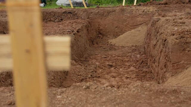Freshly excavated foundation trench on a building construction site, with dirt and sand ready for pouring concrete to create the base for a new home or building structure in progress