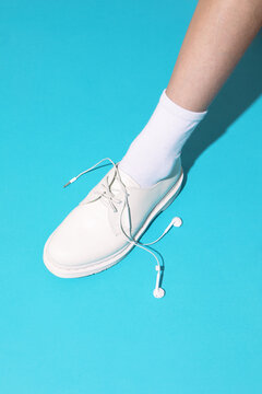 Minimalist sneaker with shoelace tangled in headphone cable