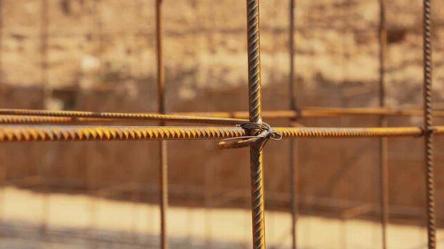 Steel reinforcement bars forming a sturdy grid structure for a building's concrete foundation, with the camera smoothly panning downwards along the rusty, wired together metal rods