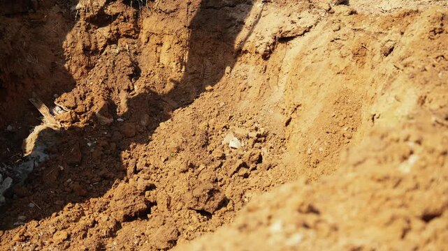 Close up of a powerful excavator bucket digging into the earth at a construction site, scooping up soil and rocks to create a trench for building foundations or utility lines