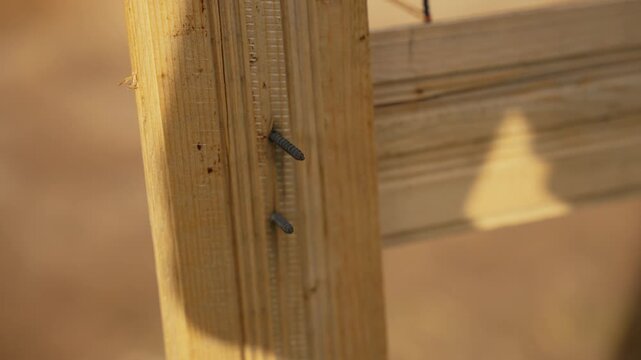 Dramatic shadow of an object slowly passing over a wooden fence post with screws under bright sunlight, symbolizing the relentless and constant passage of time during a sunny day