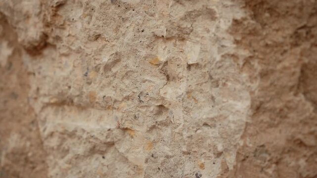 Clean water gradually soaks into a dry, porous rock surface, changing its color from light beige to a darker, damp brown as it gets absorbed, revealing the stone's rough texture