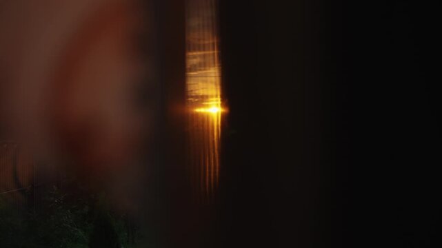 Abstract and distorted view of a person looking through a peephole, revealing a golden light from a streetlight outside, creating a sense of mystery, surveillance, and suspense at night