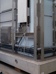 Fototapeta premium A corner of a prefabricated module with a steel frame, pipes and cabling on a concrete base.