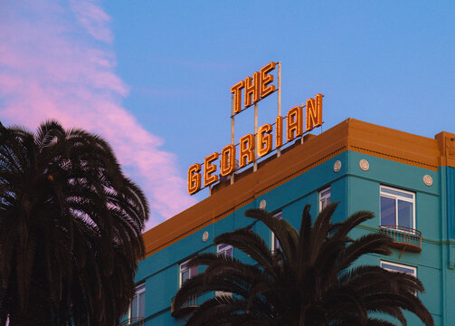 An iconic hotel sign reading The Georgian capturing the essence of retro design, juxtaposed with a stunning pink sky at dusk, evoking a sense of nostalgia and timeless charm.