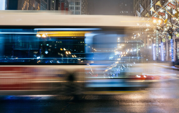 A motion-blurred image of a bus cruising through a lively Chicago street adorned with glowing lights, encapsulating the urban pulse and festive vibe of the city.