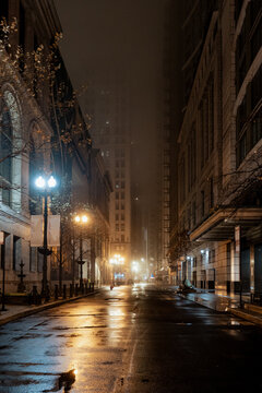 A tranquil city street at night, illuminated by serene streetlights, reflecting the quiet atmosphere created by the rain on the pavement, inviting exploration and calmness.