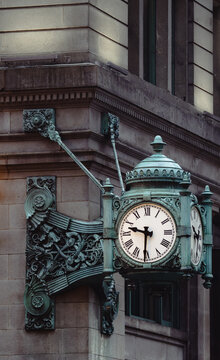 A beautifully detailed vintage clock on a building fa&ccedil;ade, showcasing intricate design and architecture that enhances the character of the urban landscape nearby.