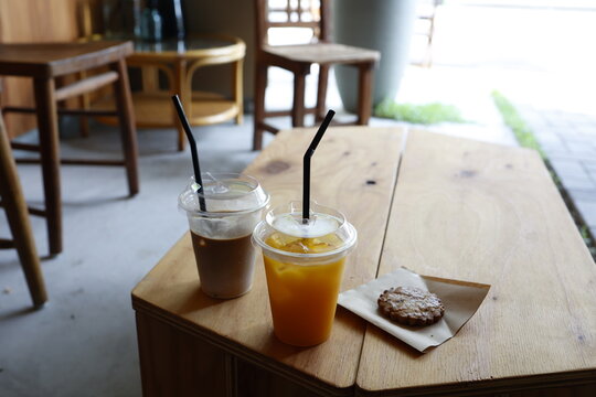 カフェ店内のドリンクとクッキー。オレンジジュースとコーヒー。木製テーブル