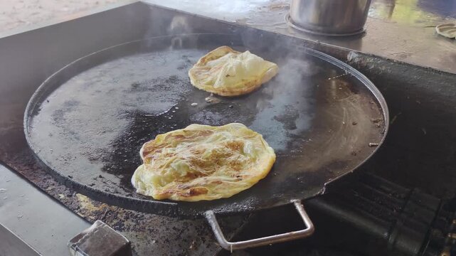 Malaysian Roti Canai Frying on a Hot Flat Grill - Traditional Asian Street Food.