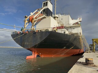 Close up view of a commercial cargo ship stern and rudder assembly floating at harbor water during port operations. © Iryna