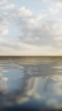 Water reflects the colors of the sky during sunrise. Clouds float above the horizon as the day begins. The scene shows a beach view with still water and natural beauty.