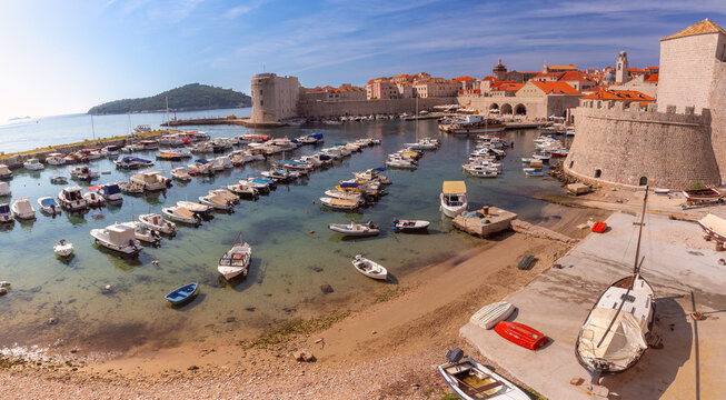 Panoramic view of Dubrovnik Old Harbor with boats, medieval city walls, and historic architecture in Dubrovnik, Croatia.