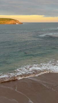 Gentle waves lap at the shore at Kings Beach in South Australia at sunset in 4k vertical footage