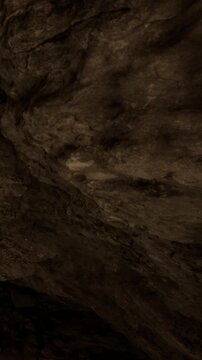 Bright light shines on a thick rock formation in a cave. The textured surfaces show shadows and grooves. The cave walls appear rough and layered, creating a natural atmosphere.