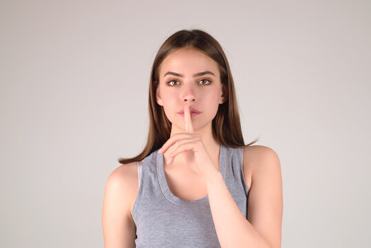 Beauty and silence concept. Portrait of attractive funny young lady showing shhh taboo sign with finger to lips over studio background, isolated. Shhh sign, facial expression, secret.