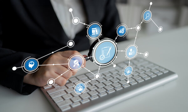 A business professional uses a magnifying glass to analyze data while surrounded by digital icons, emphasizing technology, research, and communication in a modern workspace. Crux