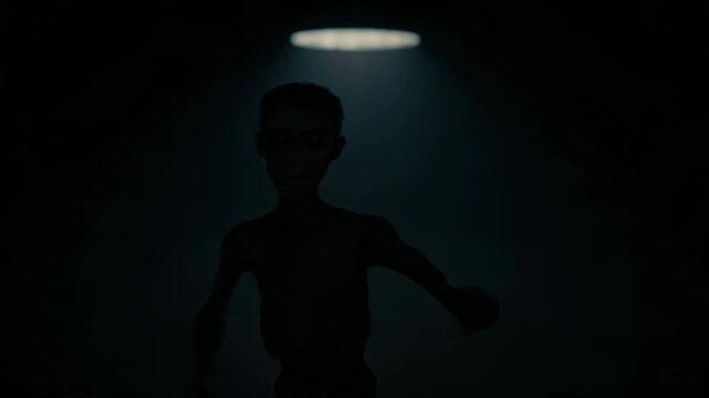 Humanoid figure walking forward from dark background in studio light. Creepy thin man emerging from shadow towards camera for horror or thriller concept sequence