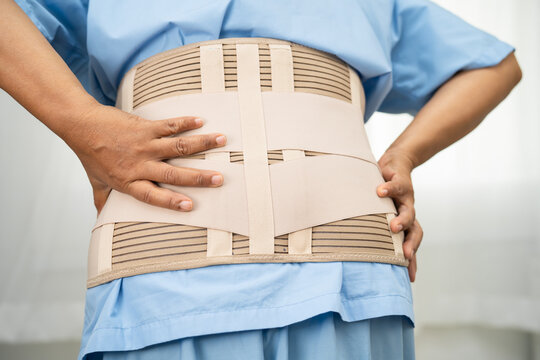 Asian lady patient wearing back pain support belt for orthopedic lumbar with walker.