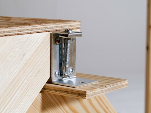 Stair stringer connector bracket fastened to framing at the base in sharp focus under single directional light