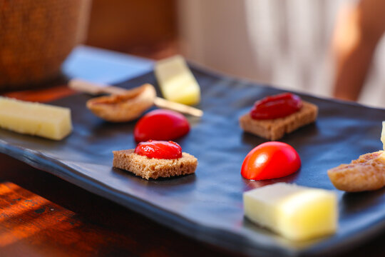 A Mediterranean appetizer plate with tomato, cheese, and bread sits in warm sunlight in Santorini, Greece, highlighting fresh local flavors.