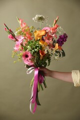 Obraz premium Woman with bouquet of beautiful vibrant flowers on olive background, closeup