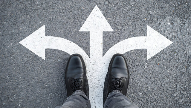 Business person standing at crossroads making decision with three painted directional arrows on asphalt decision crossroads business direction strategy opportunity pointing navigation