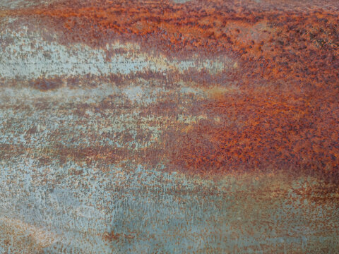 Macro view of a corroded metal surface highlighting rich orange-brown rust blending with faded steel-blue hues
