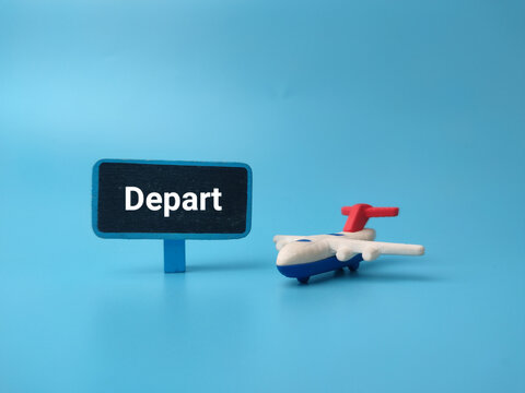 A toy airplane placed beside a small black sign board featuring the word Depart against a bright blue background