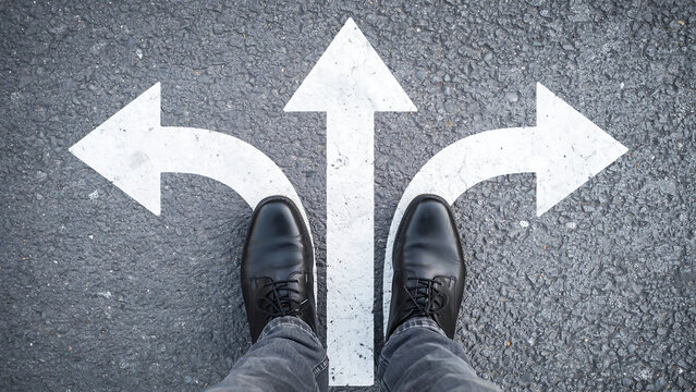 Business person standing at a three way intersection path decision point with decision direction business motivation strategy junction leadership opportunity navigation planning thinking