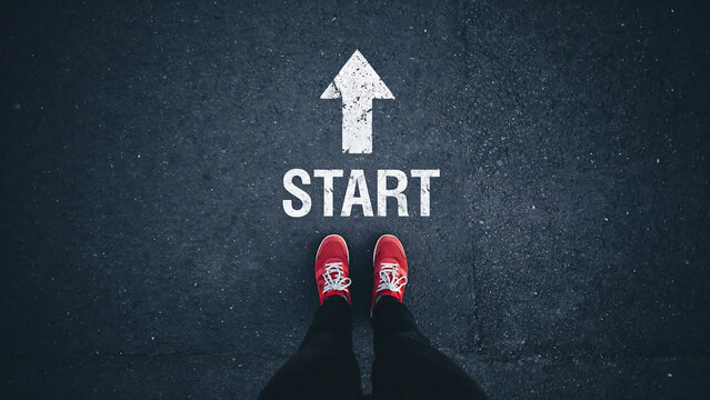 Starting point concept person standing on asphalt road with painted white arrow sign direction beginning motivation movement opportunity lifestyle perspective