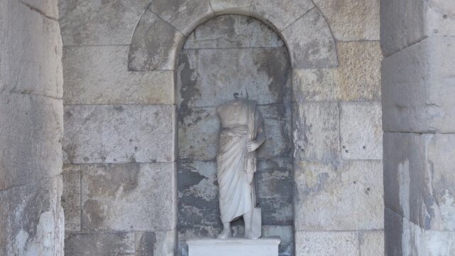 Headless ancient roman statue standing in a stone niche at the Odeon of Herodes Atticus in Athens