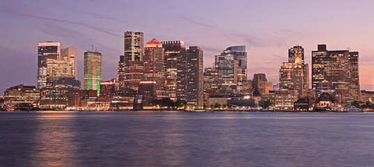 Naklejka premium Boston skyline illuminated at dusk with Atlantic Ocean on the foreground, USA