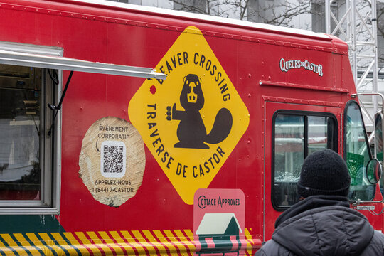 MONTREAL, CANADA, 23 December 2025 : Food truck, beaver crossing sign, red vehicle, winter scene, street food, outdoor event