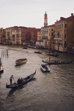 Traditional Gondolas and Motorboats Navigating a Wide Canal Surrounded by Historic Palaces with a Bell Tower