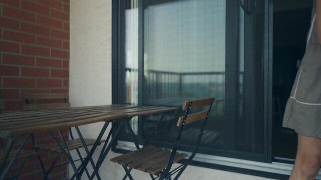 Woman placing a folding chair at a bistro table on a balcony