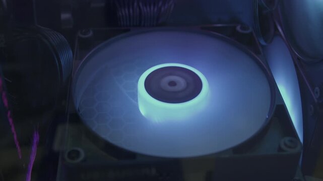 Close-up slow-motion shot of a computer liquid cooling radiator fan spinning and glowing with warm ambient lighting inside a custom gaming rig.