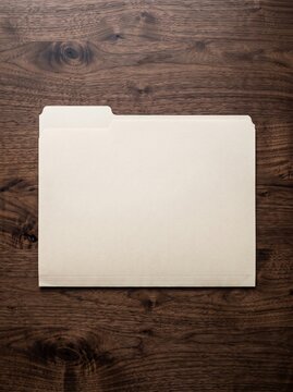Blank manila file folder on a dark wood grain background