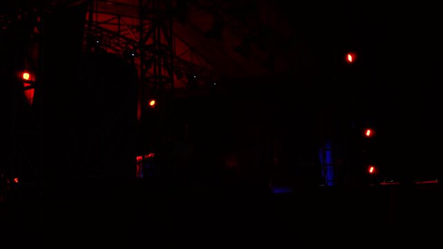 Red lights shining on empty concert stage rigging at night